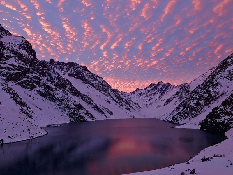 A Laguna del Inca entre montanhas nevadas, com o céu rosa do fim de tarde