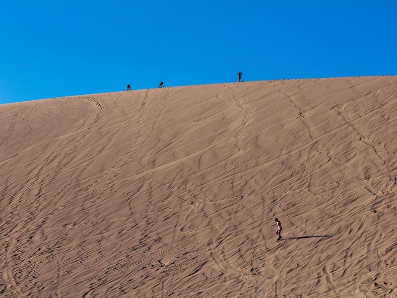 Pessoas fazendo sandboard na duna do Valle de la Muerte