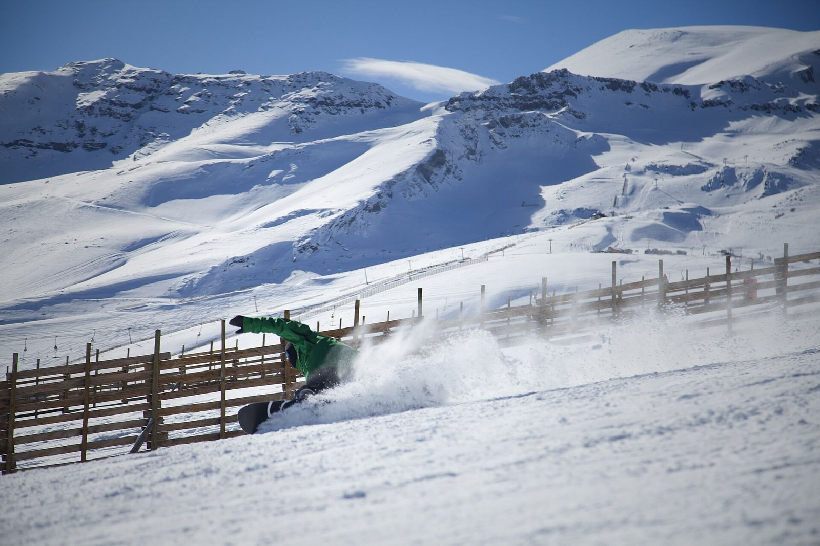 Snowboarder descendo a pista de El Colorado, com as montanhas nevadas ao fundo