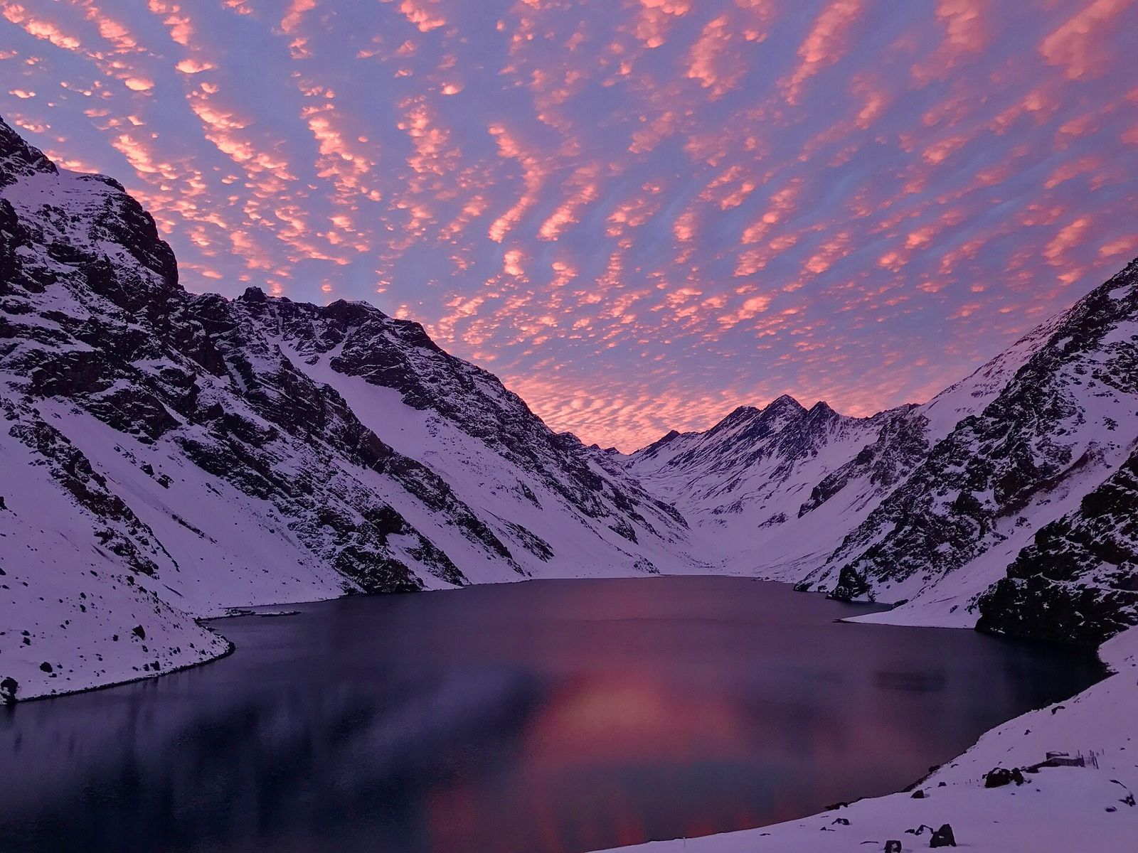 A Laguna del Inca entre montanhas nevadas, com o céu rosa do fim de tarde