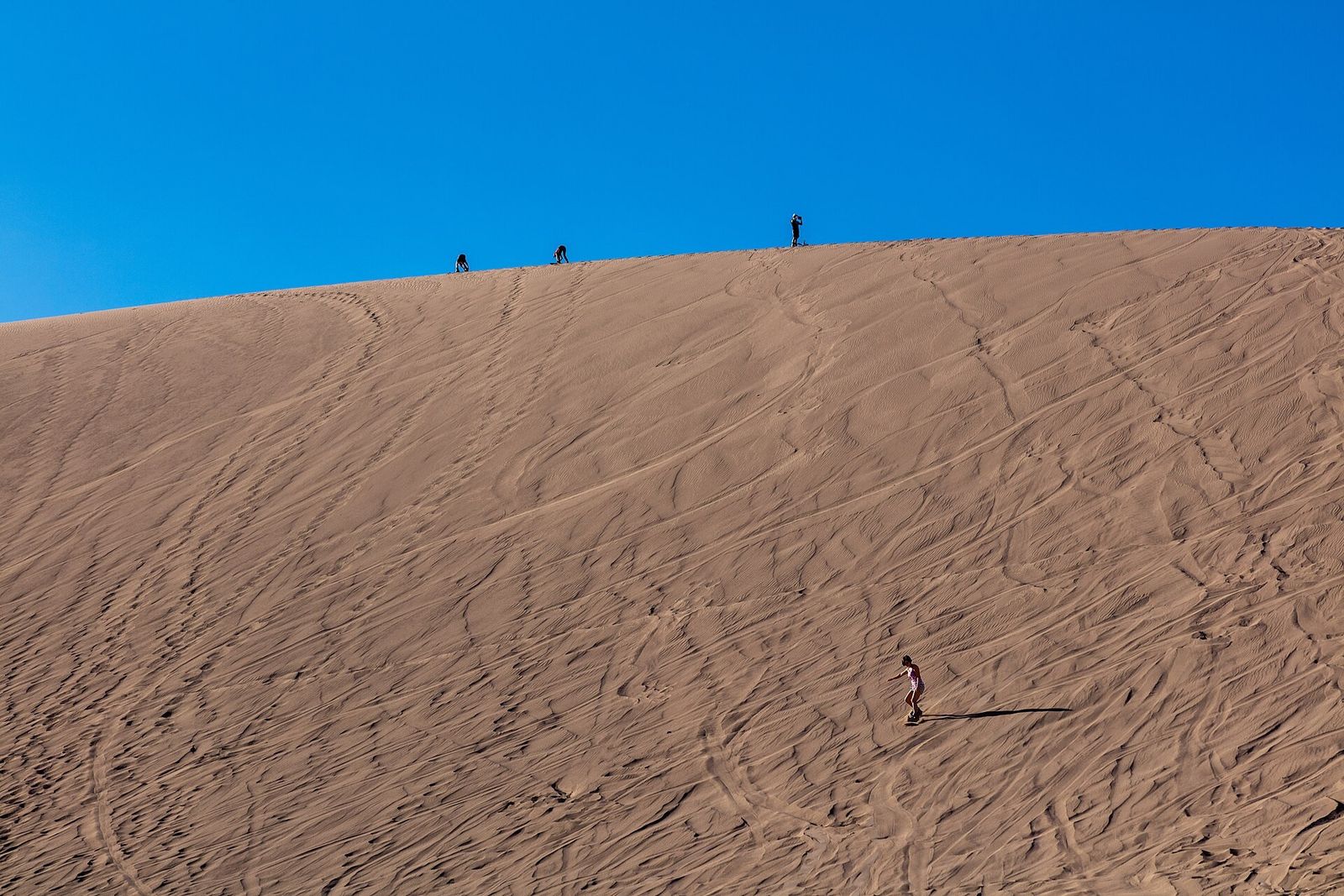 Pessoas fazendo sandboard na duna do Valle de la Muerte